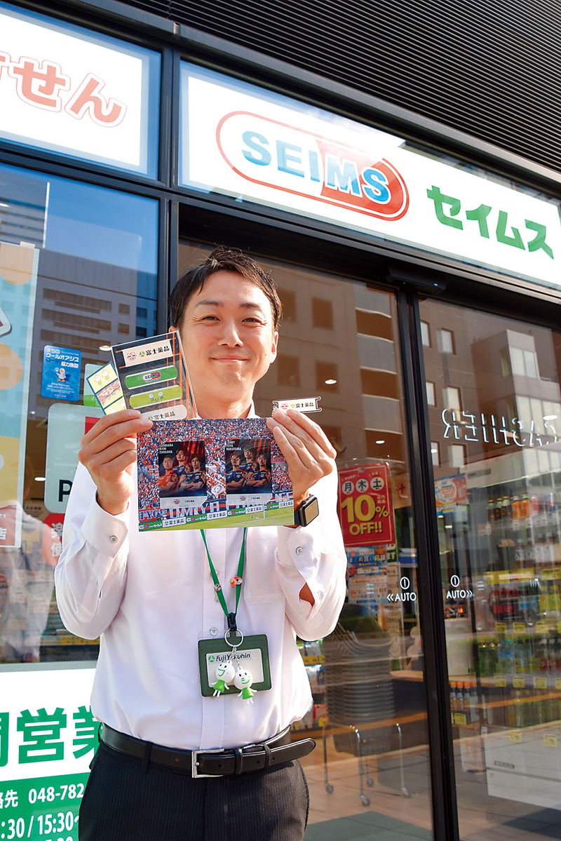限定ノベルティを紹介する富士薬品総務部広報戦略室の古川大介係長＝8日午後、さいたま市大宮区