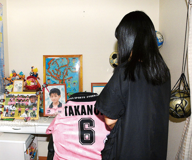 孝徳さんの写真や遺品が飾られた学習机を見つめながら、思いを語る母代里子さん＝熊谷市内