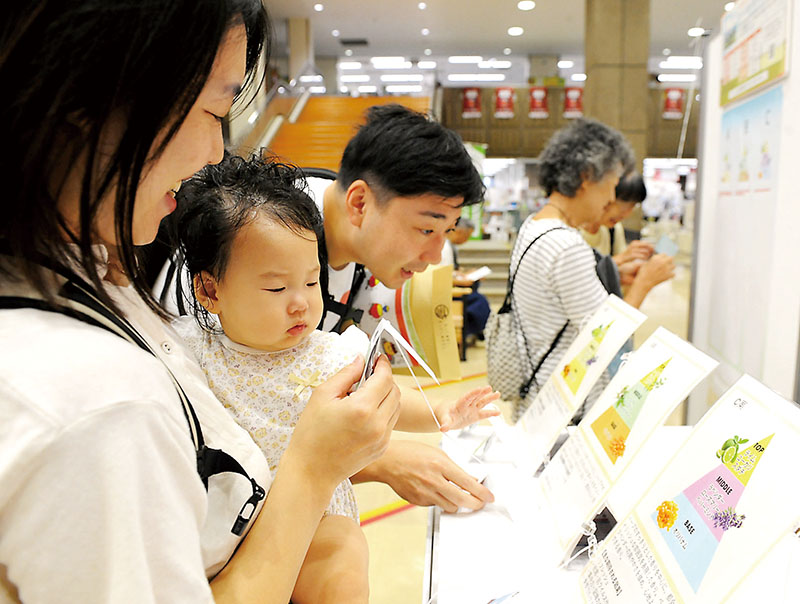 3種の香りのテスターを体験する安生さん一家。右奥にシールを貼って投票できる＝2日、さいたま市浦和区の浦和区役所