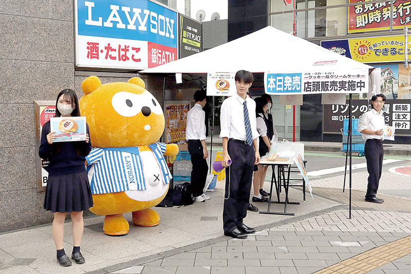 販売初日にローソン北朝霞駅前店付近で、販売キャンペーンに参加する新座総合技術高校の生徒ら＝3日正午ごろ、JR武蔵野線北朝霞駅前