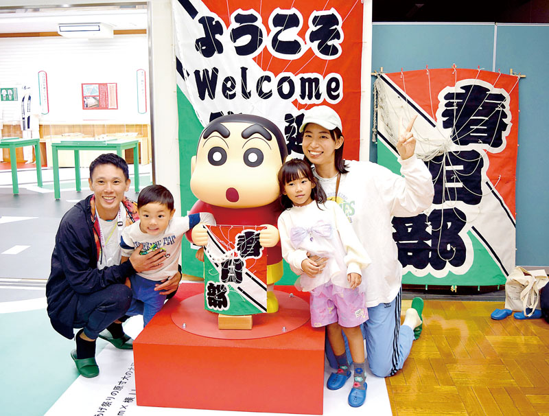 しんちゃんの新モニュメントと記念撮影する親子＝11日午後、春日部市大凧文化交流センター「ハルカイト」