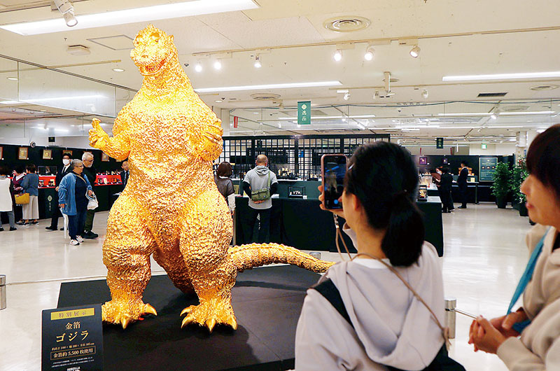 金箔ゴジラを撮影する来場者＝16日、さいたま市大宮区のそごう大宮店