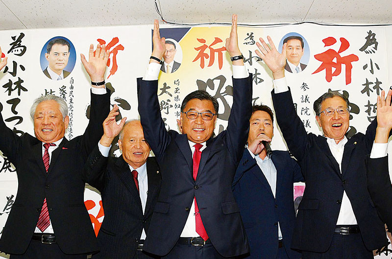 無投票で再選が決まり、万歳する小林哲也氏（中央）＝19日午後5時5分ごろ、熊谷市広瀬の選挙事務所