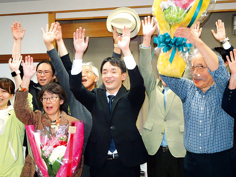 鶴ケ島市長選で初当選し支持者らと万歳する小川尋海氏（中央）＝26日夜、鶴ケ島市内