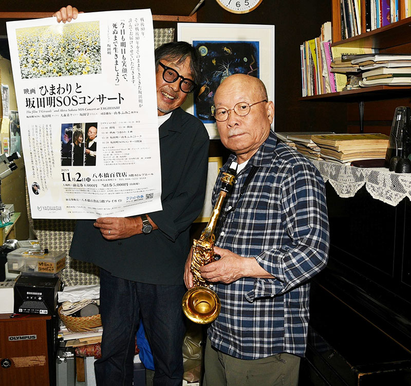 熊谷市で初めてコンサートを行う坂田明さん（右）と、ポスターを手に来場を呼びかける代島治彦さん＝蕨市内の坂田さん宅