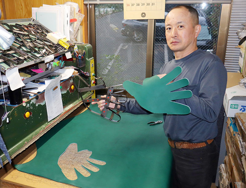 手の型で色付きの牛革の型抜きをする早川和孝さん＝朝霞市栄町の作業場