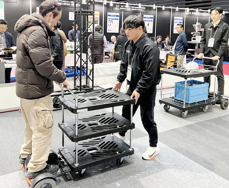 先端技術を使った台車用スクーターを体験する来場者ら＝18日、さいたま市中央区のさいたまスーパーアリーナ