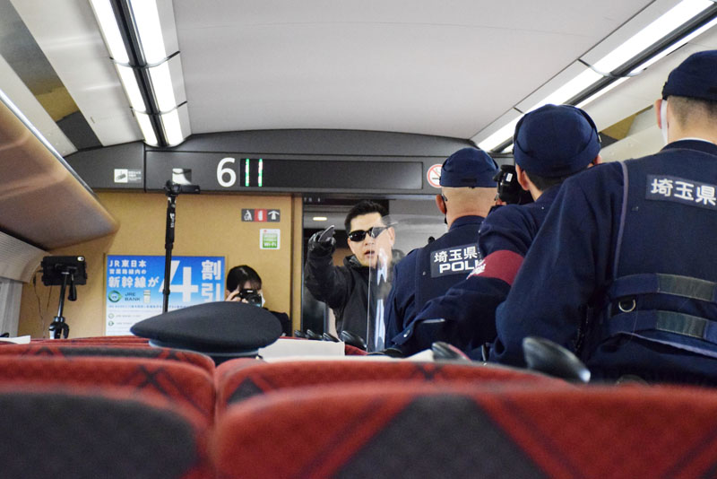 刃物を持って威嚇する不審者役に対応する警察官＝8日午後、高崎―大宮間を走行中の上越新幹線車内