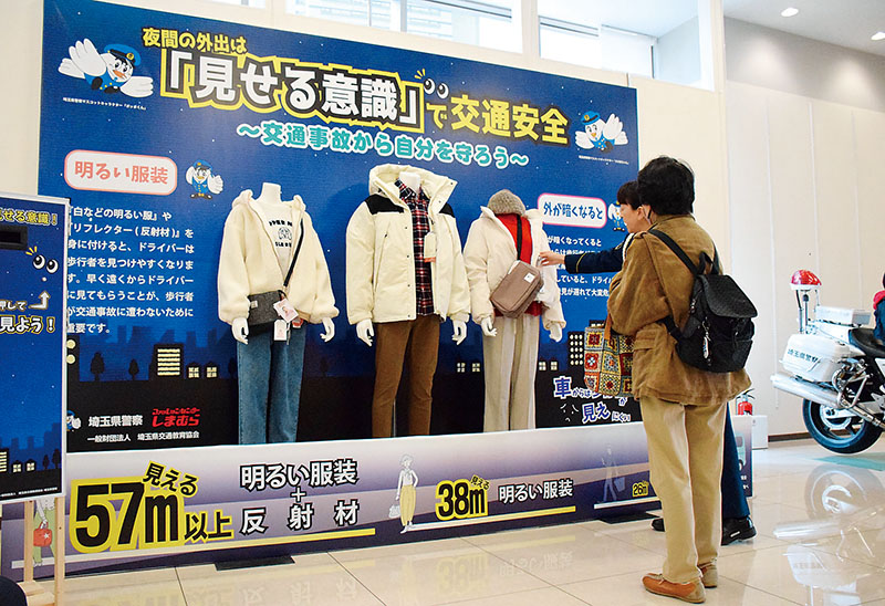 来店した人に展示されている明色系衣服のコーデを説明する警察官