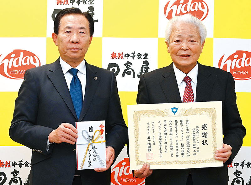 日高市の谷ケ崎照雄市長（左）に寄付金を贈呈したハイデイ日高の神田正会長＝19日、さいたま市大宮区