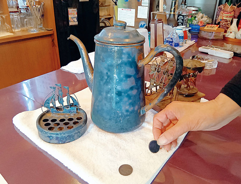 青色に変色した飲食店のポットと10円玉＝17日、八潮市内