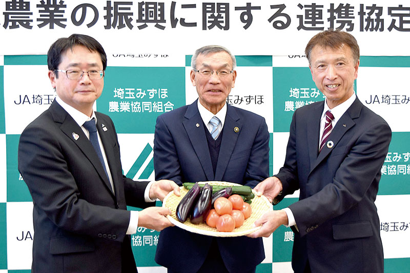 野菜を手に連携をアピールする（左から）JA全農の日比健常務理事、木村純夫市長、JA埼玉みずほの遠藤美行代表理事組合長＝18日午後、幸手市神明