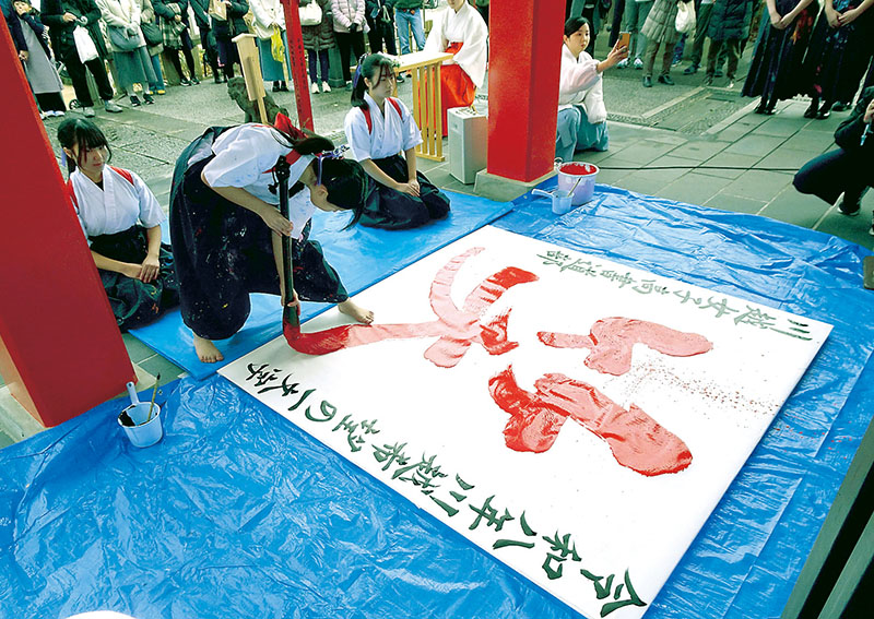 「希望の一文字」の「笑」を揮毫する川越女子高校書道部の生徒＝20日午後、川越市南通町の川越八幡宮