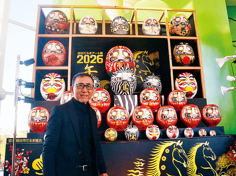 越谷だるまと自らデザインしただるまを紹介する花房茂さん＝越谷市の越谷レイクタウン
