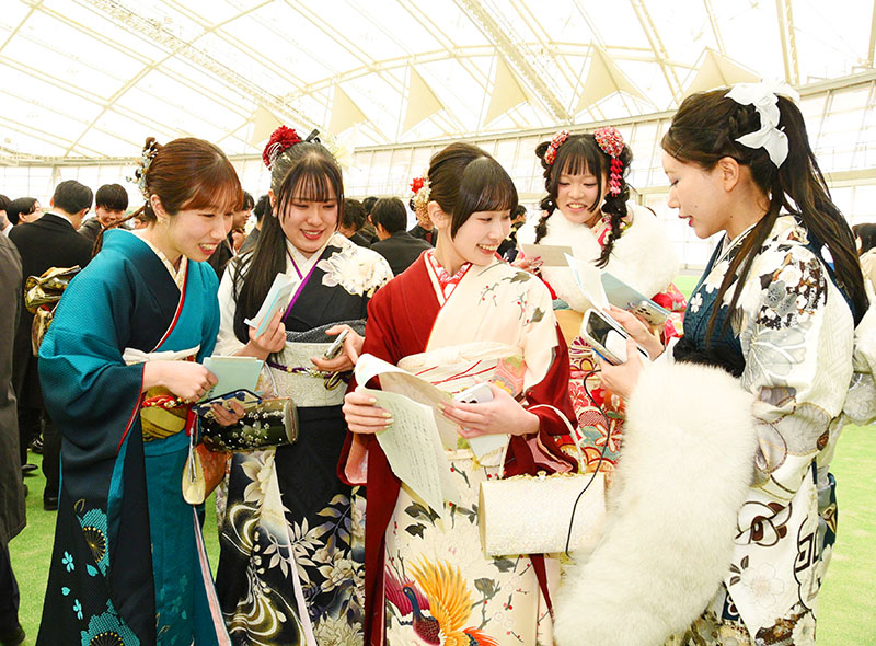 10歳のころ、20歳になった自分へ宛てて書いた手紙が返却され、旧友と見せ合う式典の出席者たち＝11日、熊谷市上川上の彩の国くまがやドーム