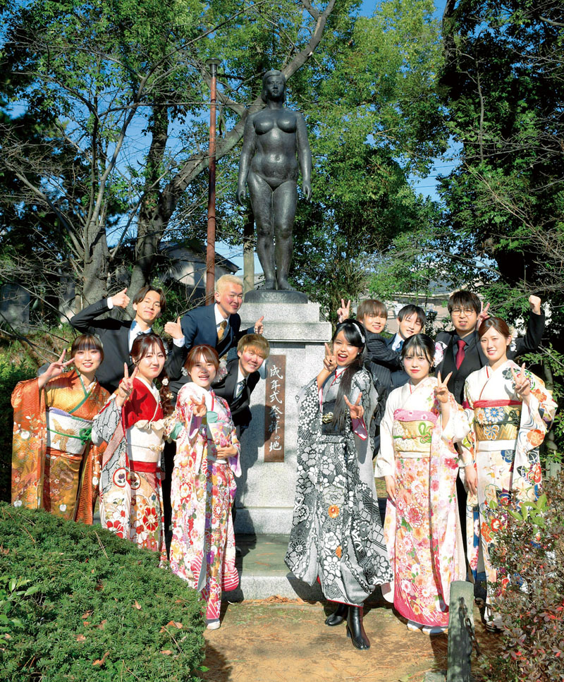 「成年式発祥の地記念像」の前に並ぶ蕨市成年式実行委員＝12日午後、蕨市中央の城址公園