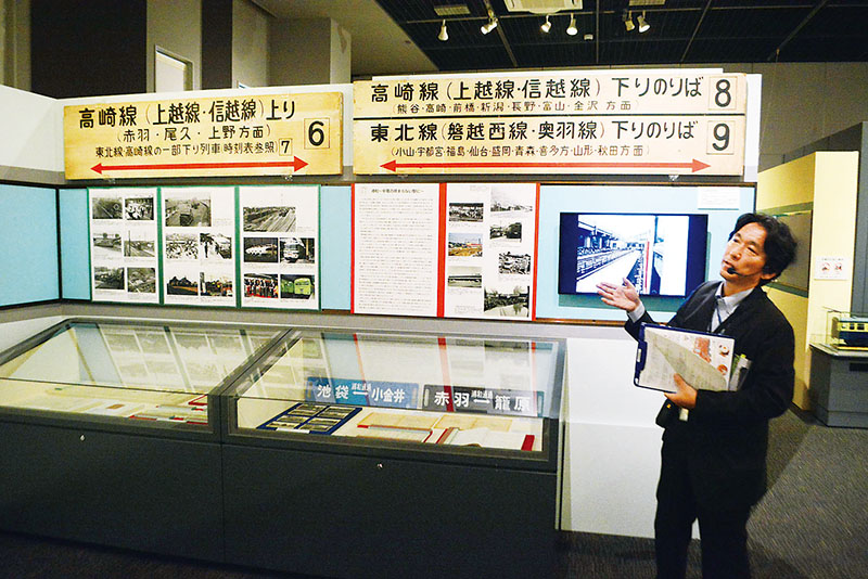 大宮駅のあゆみを紹介する主幹学芸員の奥原哲志さん。解説パネルや写真のほか、かつて使われていた乗場案内なども展示されている