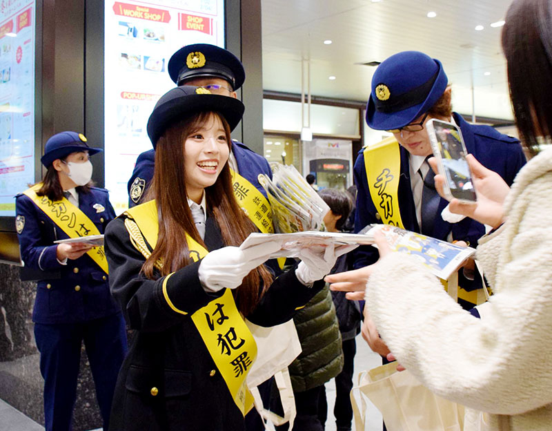 駅利用者に痴漢防止の啓発品を配る谷村優真さん（左）