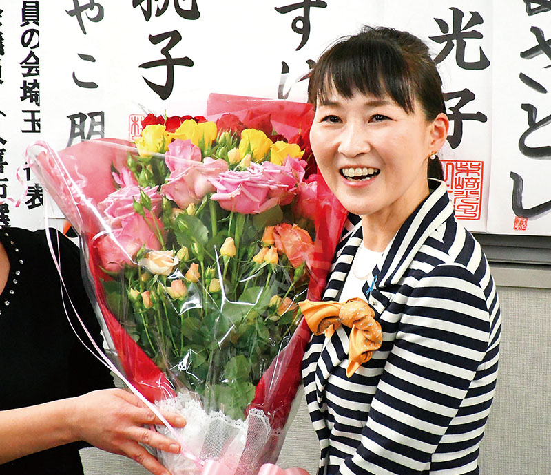 支援者から当選祝いの花束を受け、笑顔を見せる岡村ゆり子氏＝1日午後11時過ぎ、川口市の岡村氏事務所