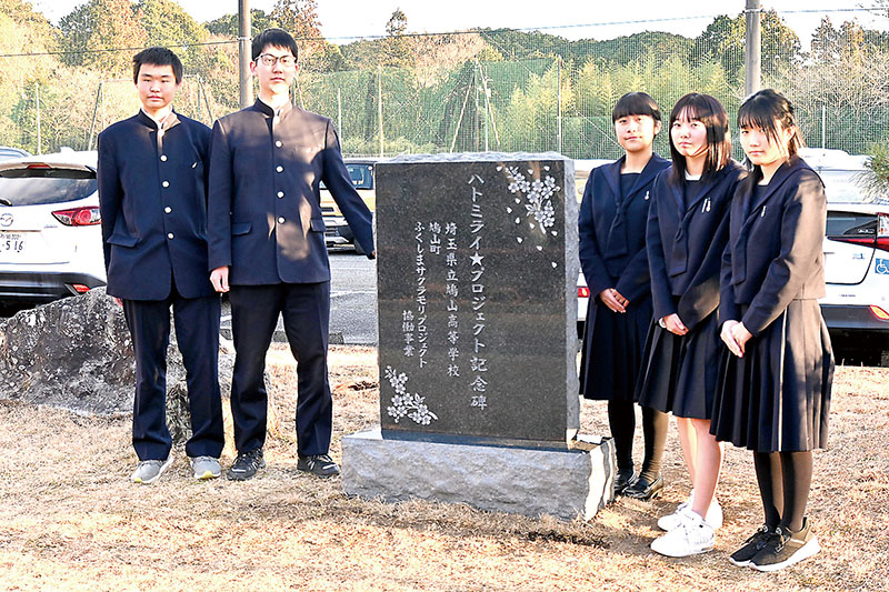 ハトミライ☆プロジェクトの活動を伝える記念碑と、鳩山高校生徒会の生徒たち＝越生町西和田の越生高校