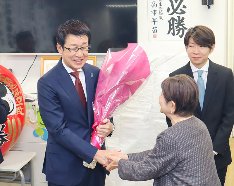 7選を果たし、支援者から花束を受け取る15区・田中良生氏(左)