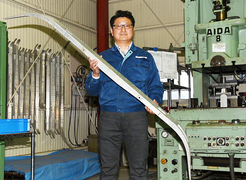 パンタグラフの舟体を手にする松田製作所社長の松田健さん＝熊谷市妻沼