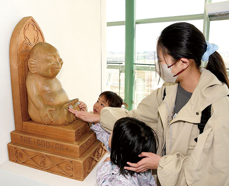 幸運を呼び込もうとビリケン像の足裏をなでる子どもたち