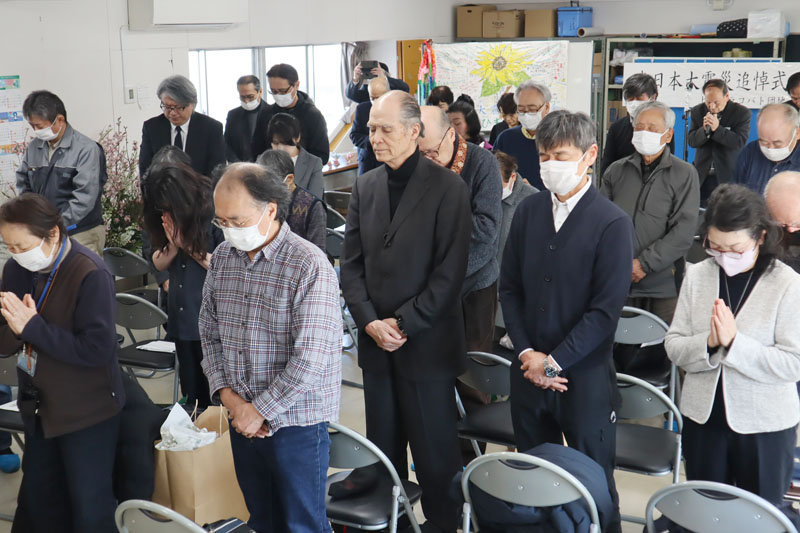 静かに目をつむり黙とうする参列者たち＝11日午後2時46分、上尾市上の県営シラコバト団地集会所