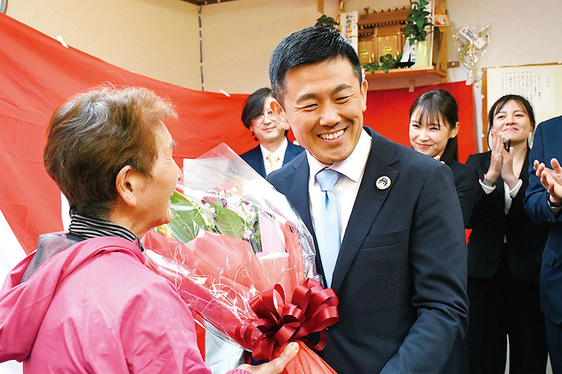 3選を祝う花束を受け取り、笑顔を見せる菅原文仁氏＝15日午後6時10分ごろ、戸田市の選挙事務所