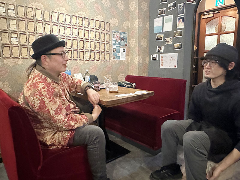 「心からリラックスできるかけがえのない場所」と話す常連客男性の言葉に耳を傾けるジョージさん（右）＝さいたま市見沼区のカフェ「ミチクサ」