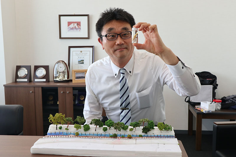 ムサシノジュズカケハゼの標本を見つめる橋本健一さん。手前は自作した水辺のイメージ模型＝3月27日、さいたま市中央区の大日本ダイヤコンサルタント関東支社