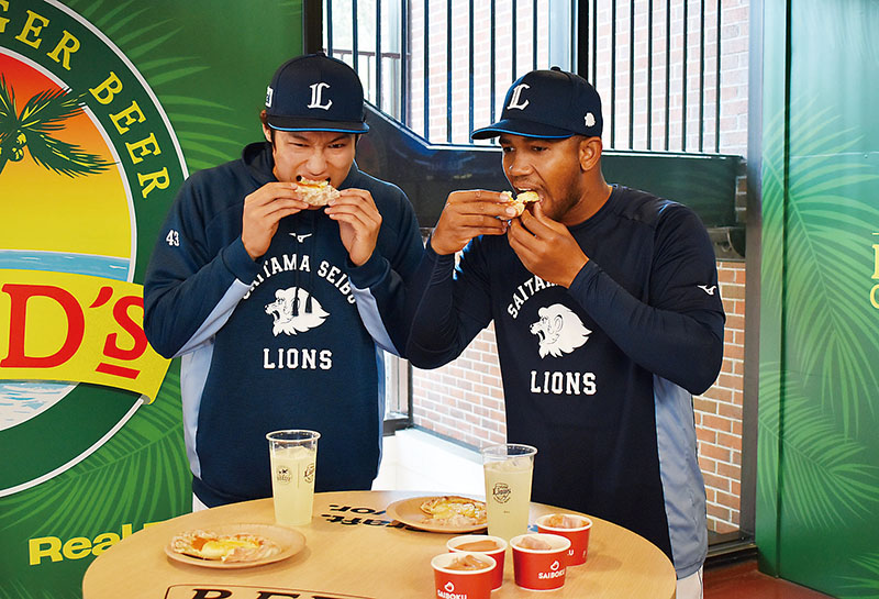 新グルメのピザを試食する羽田慎之介投手（左）とエマニュエル・ラミレス投手＝3日午後、所沢市上山口