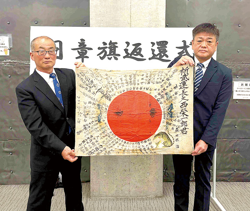 新井靖雄会長（左）から日章旗を返還された西嘉章さん＝5月28日、秩父市役所