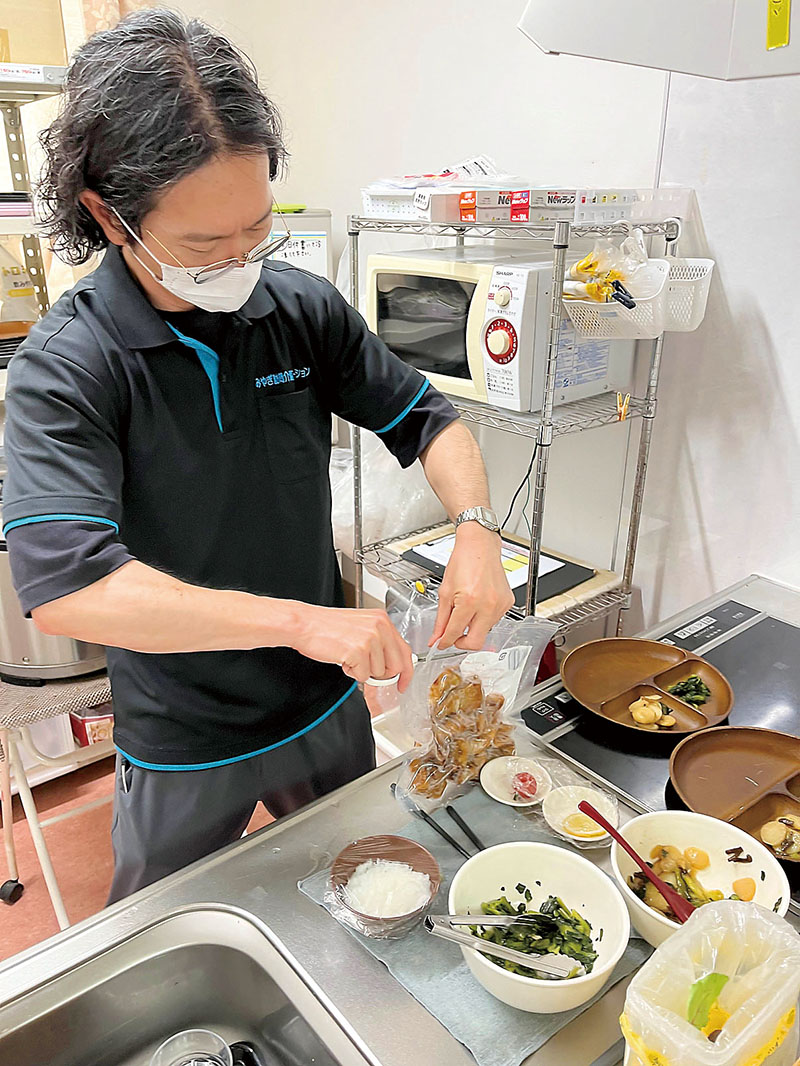 パック詰めのおかずを湯せん解凍し取り分けていく職員＝2日、伊奈町のメディカルホームサルーテ伊奈