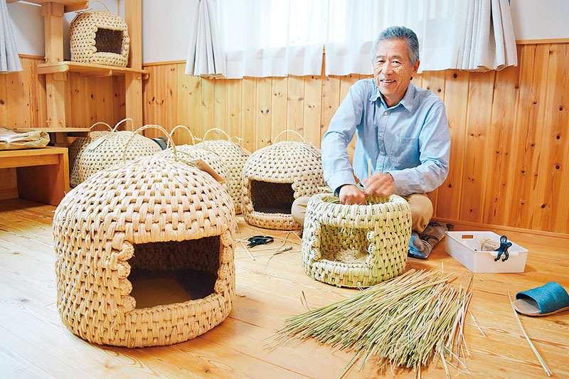 稲わらを編んで猫つぐらを作る太田正志さん＝久喜市南