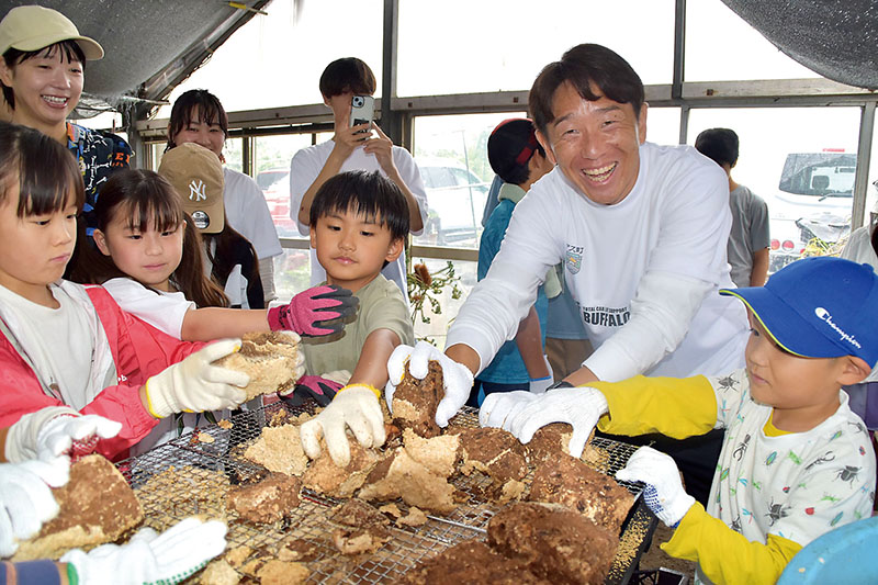 シイタケ栽培で使われた菌床を楽しそうに削る宇賀神友弥さん（右から2人目）と子どもたち＝20日、さいたま市緑区
