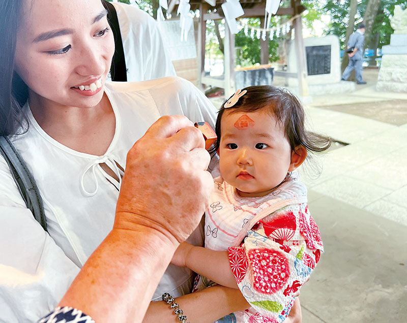 おでこに朱印を押してもらう加藤凜叶ちゃん。左が母雛乃さん＝1日、さいたま市岩槻区の冨士浅間神社