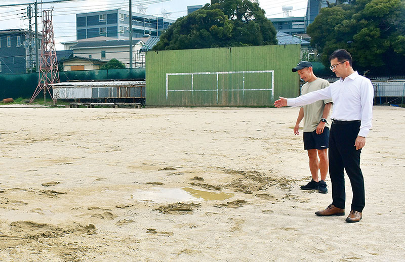 水はけの悪いグラウンドの人工芝化に奮闘する県立浦和高校サッカー部の本田哲也監督（左）と杉田和明校長＝6月、さいたま市浦和区
