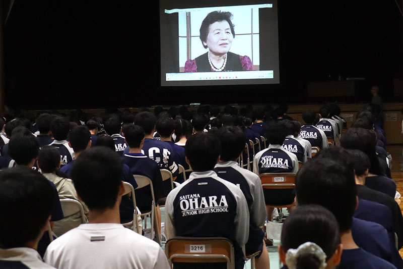 過酷な体験を語る元ひめゆり学徒隊の故与那覇百子さんの映像を見る生徒たち＝さいたま市立大原中学校体育館