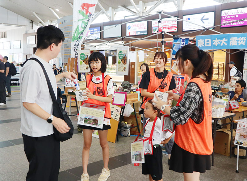 「復興支援にご協力を」と呼びかけるReVAのメンバーたち＝19日午前、JR上尾駅の自由通路
