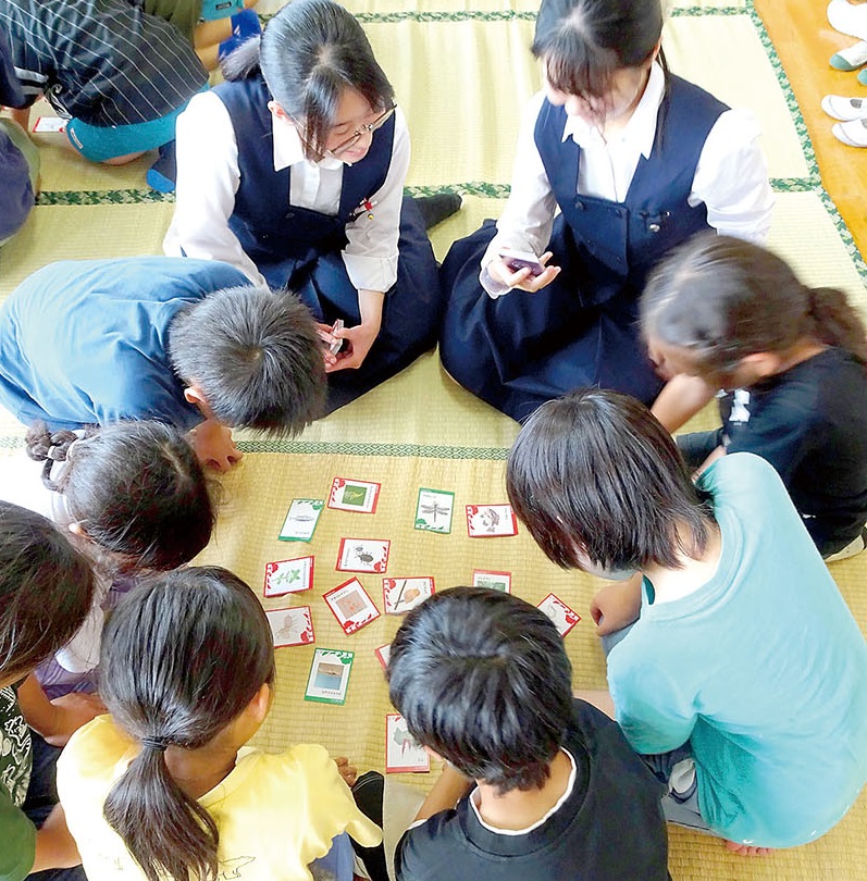 上・「外来種希少種かるた」を作成した川越女子高校生物部の部員＝17日午後、川越市内　下・川越女子高生物部員とかるたを楽しむ児童＝17日午後、川越市内