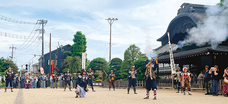 川越市立川越高校の生徒らが参加する行列の前で演舞をする鉄砲隊＝26日、川越市郭町2丁目の川越城本丸御殿