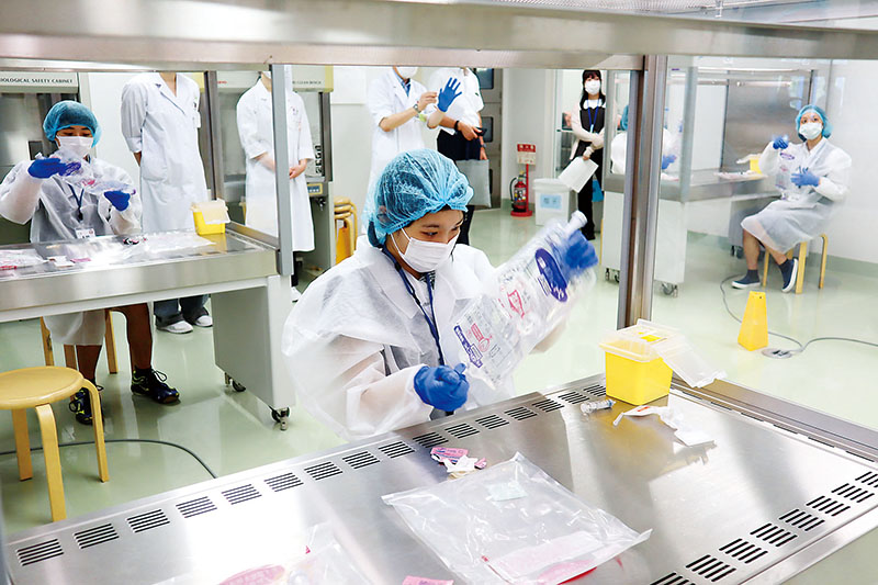 2つの薬剤を混ぜるなどの調剤体験をする高校生たち＝25日、伊奈町小室の日本薬科大学研究棟