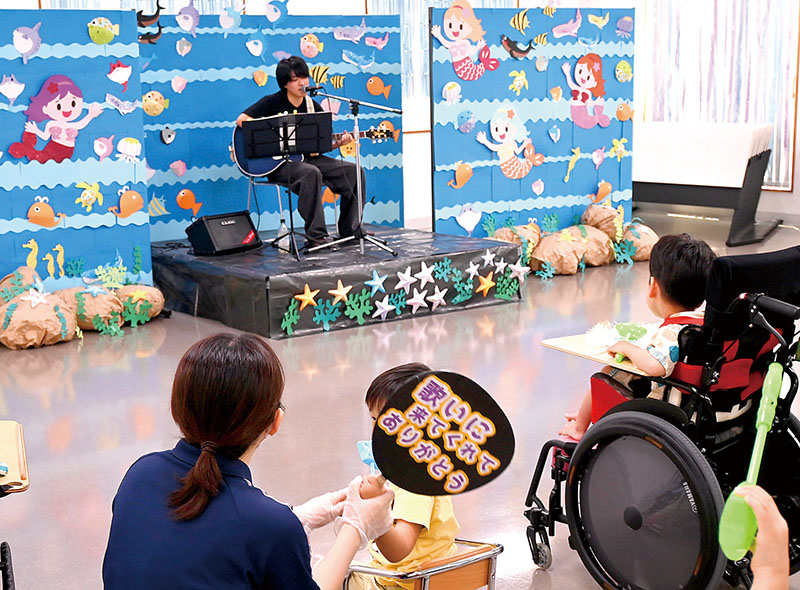 施設利用者や職員の前で歌うKIYOHARUさん＝1日、寄居町藤田の埼玉療育医療センター