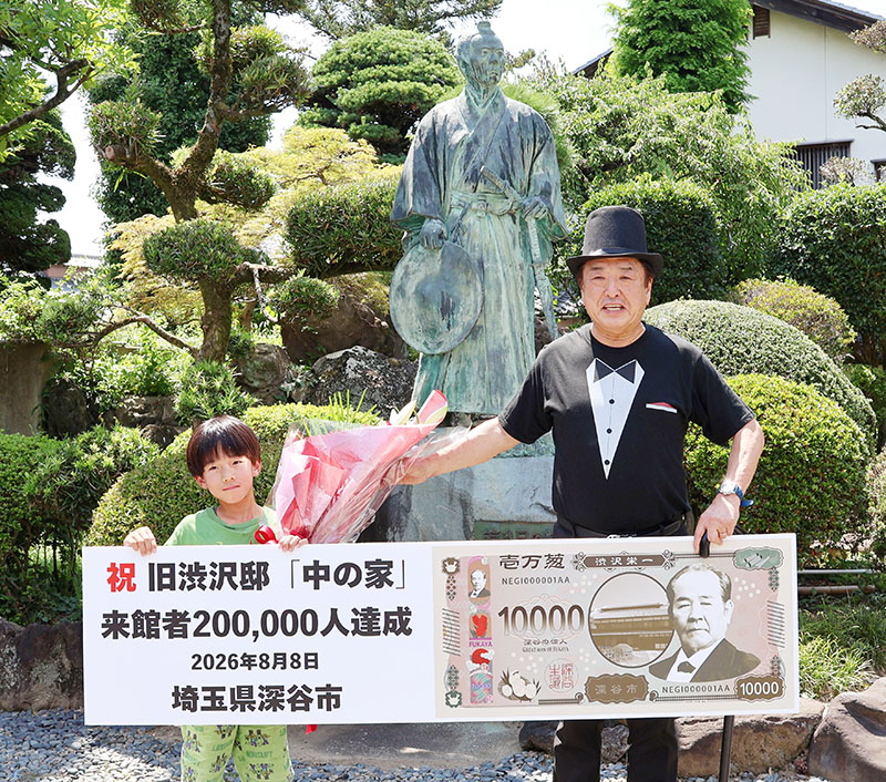 渋沢栄一の銅像の前で小島進市長（右）と記念撮影する増田陸人さん＝8日午後、深谷市血洗島「中の家」