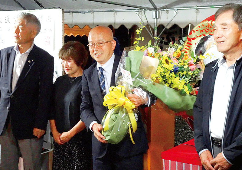 再選を果たし、支持者らから花束を受け取る大塚信一氏＝6日夜、滑川町羽尾の選挙事務所