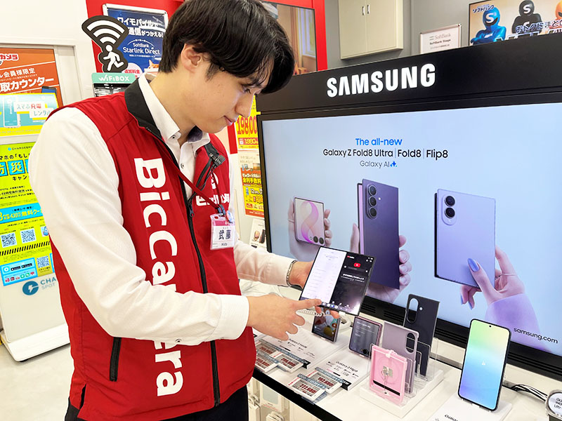 先行する他社製品の機能を説明する店舗スタッフ＝12日、さいたま市浦和区のビックカメラ浦和西口店
