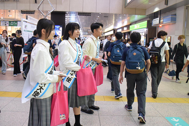 駅利用者に啓発品を配り痴漢犯罪防止を呼びかける高校生ら（左）