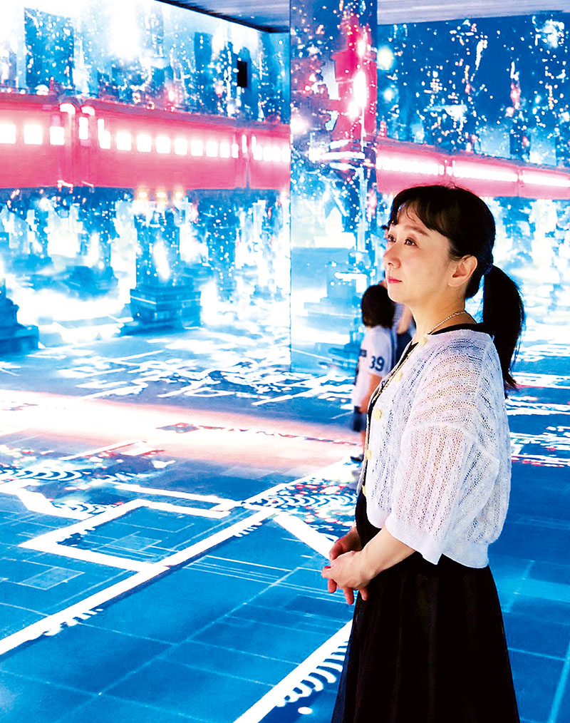 32台の4Kレーザー投影機が色鮮やかに「銀河鉄道999」の世界を映し出すイマーシブルシアターで、映像に見入る松本摩紀子さん＝8月21日、角川武蔵野ミュージアム　(C)松本零士／零時社・東映アニメーション