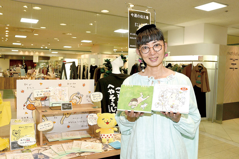 初めて作ったイラスト入り卓上カレンダーを手にすることなさん＝24日、熊谷市仲町の八木橋百貨店